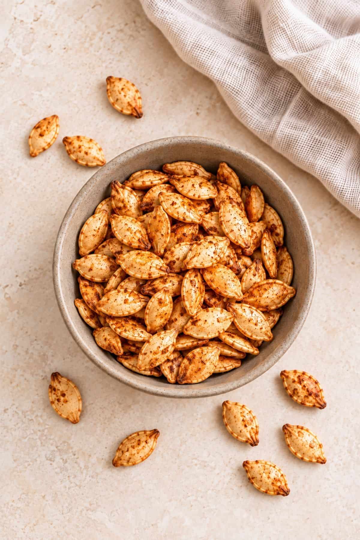 Roasted pumpkin seeds with taco seasoning served in a ceramic bowl.