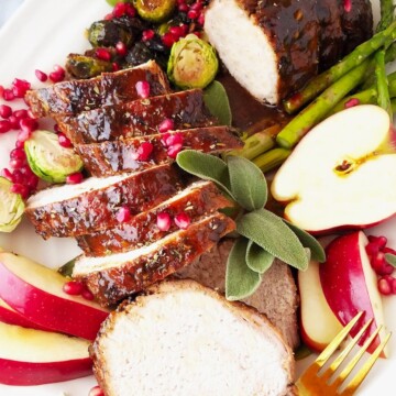 crock pot pork loin partially sliced ina platter with apples and veggies