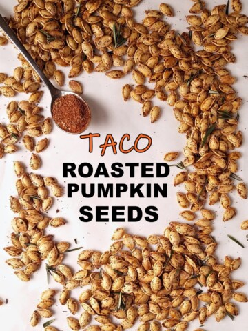 a bunch of roasted pumpkin seeds with a spoon of taco seasoning on the side