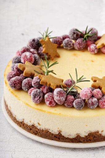 cheesecake topped with sugared cranberries and Christmas gingerbread cookies