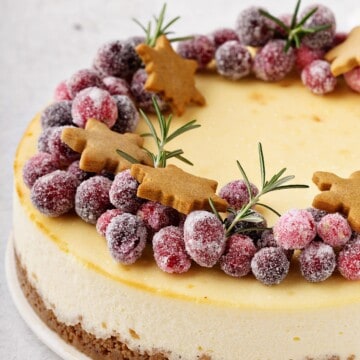cheesecake topped with sugared cranberries and Christmas gingerbread cookies