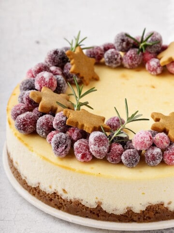 cheesecake topped with sugared cranberries and Christmas gingerbread cookies