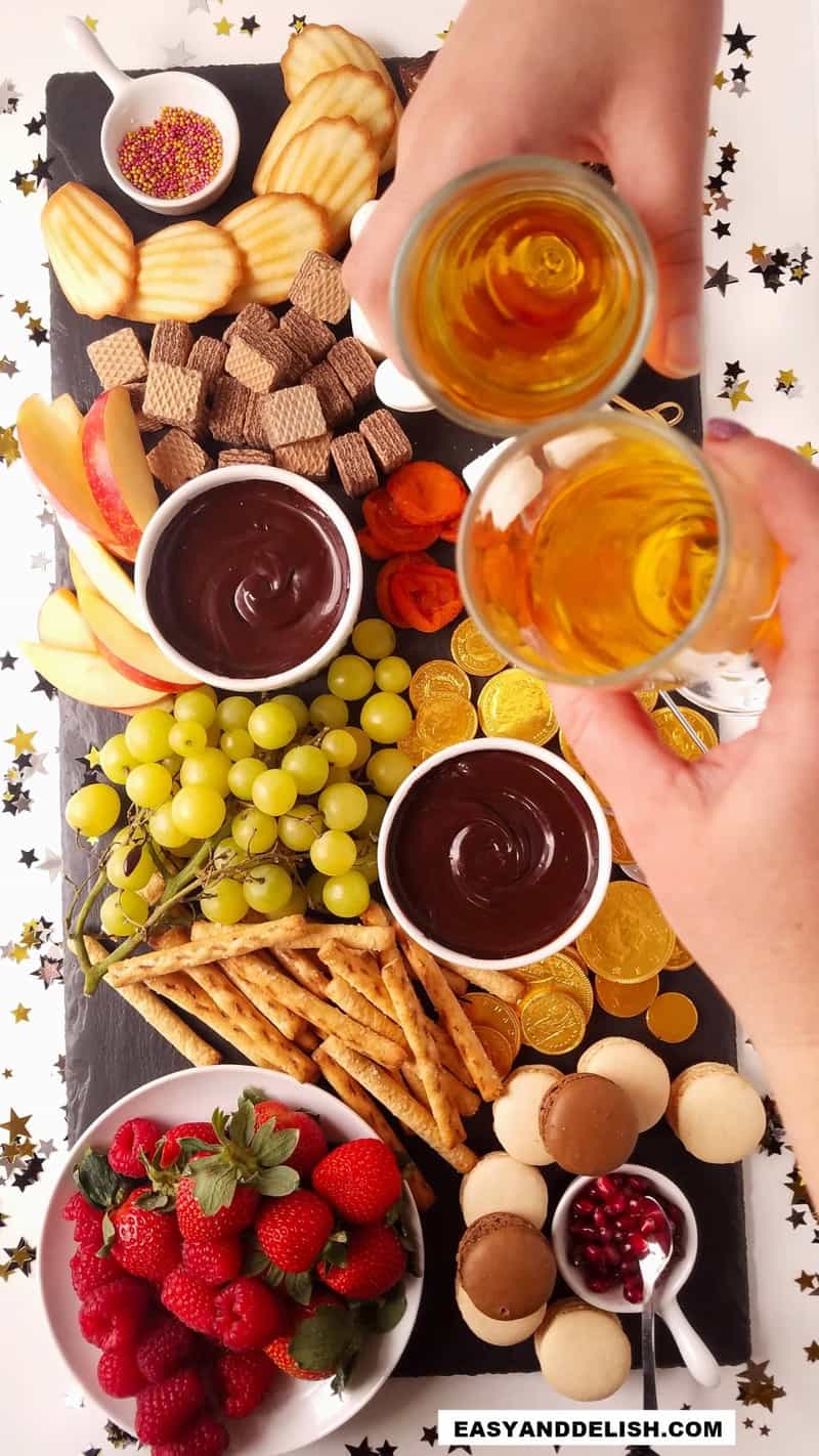 chocolate fondue and dippers on a board and champagnes glasses making a toast 