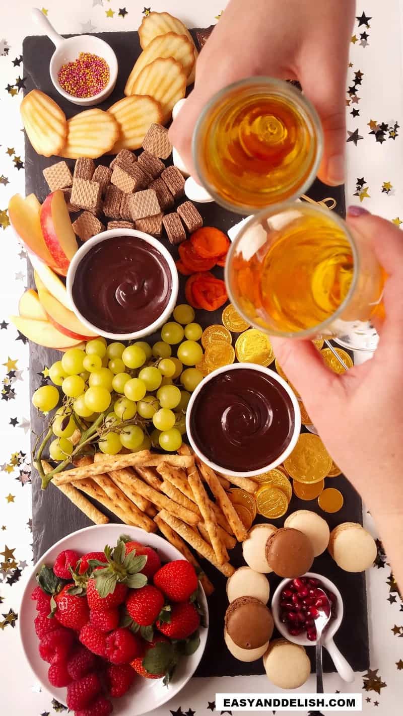 fondue de chcoolate com acompanhamentos e taças de champagne brindando o reveillón