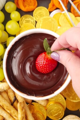 morango sendo mergulhado em fondue de chocolate