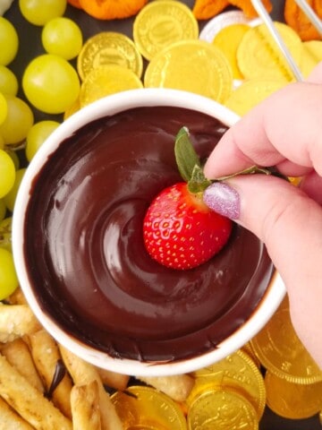 morango sendo mergulhado em fondue de chocolate