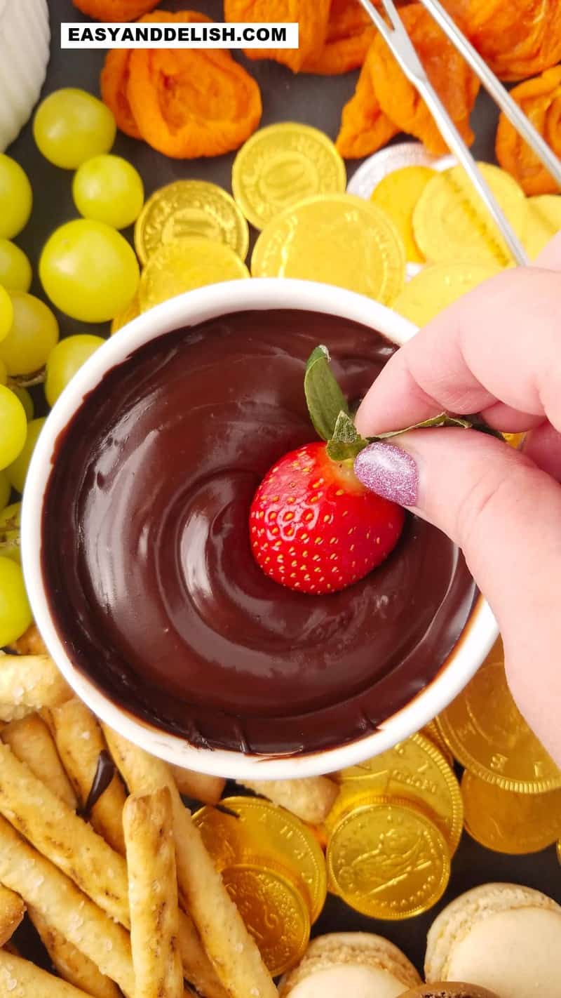 morango sendo mergulhado em fondue de chocolate