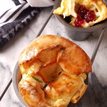 popovers in a popover pan, one whole and other open with jam