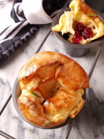 popovers in a popover pan, one whole and other open with jam