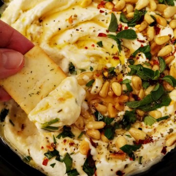 whipped feta dip in a plate and a scoop of it on a pita chip