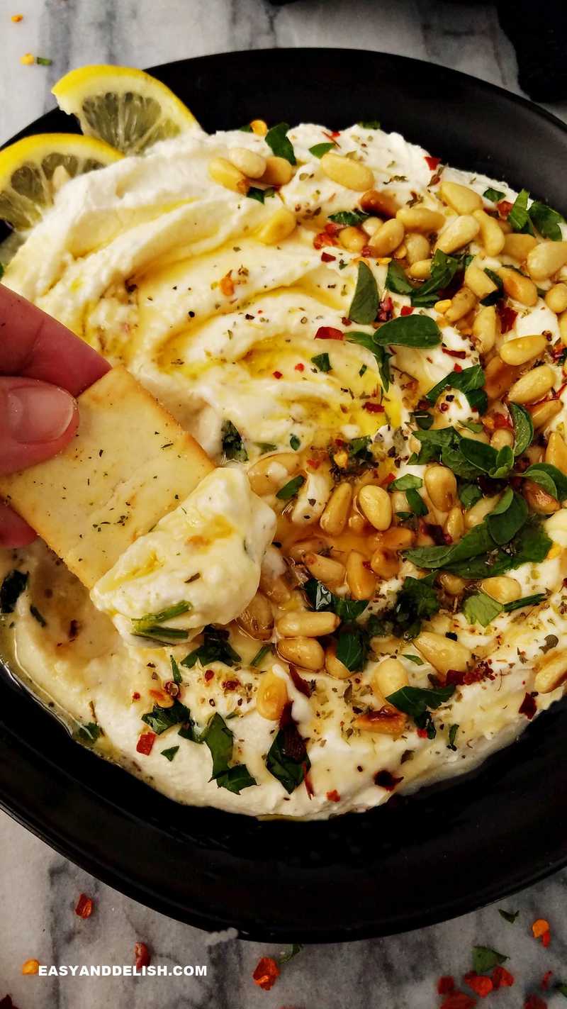 whipped feta dip in a plate and a scoop of it on a pita chip