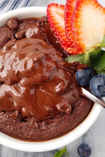 close up of baked oats with a molten chocolate center and berries
