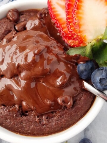 close up of baked oats with a molten chocolate center and berries