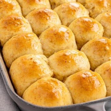 oat rolls brushed with honey butter in a baking dish