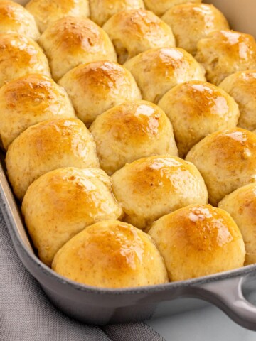 oat rolls brushed with honey butter in a baking dish