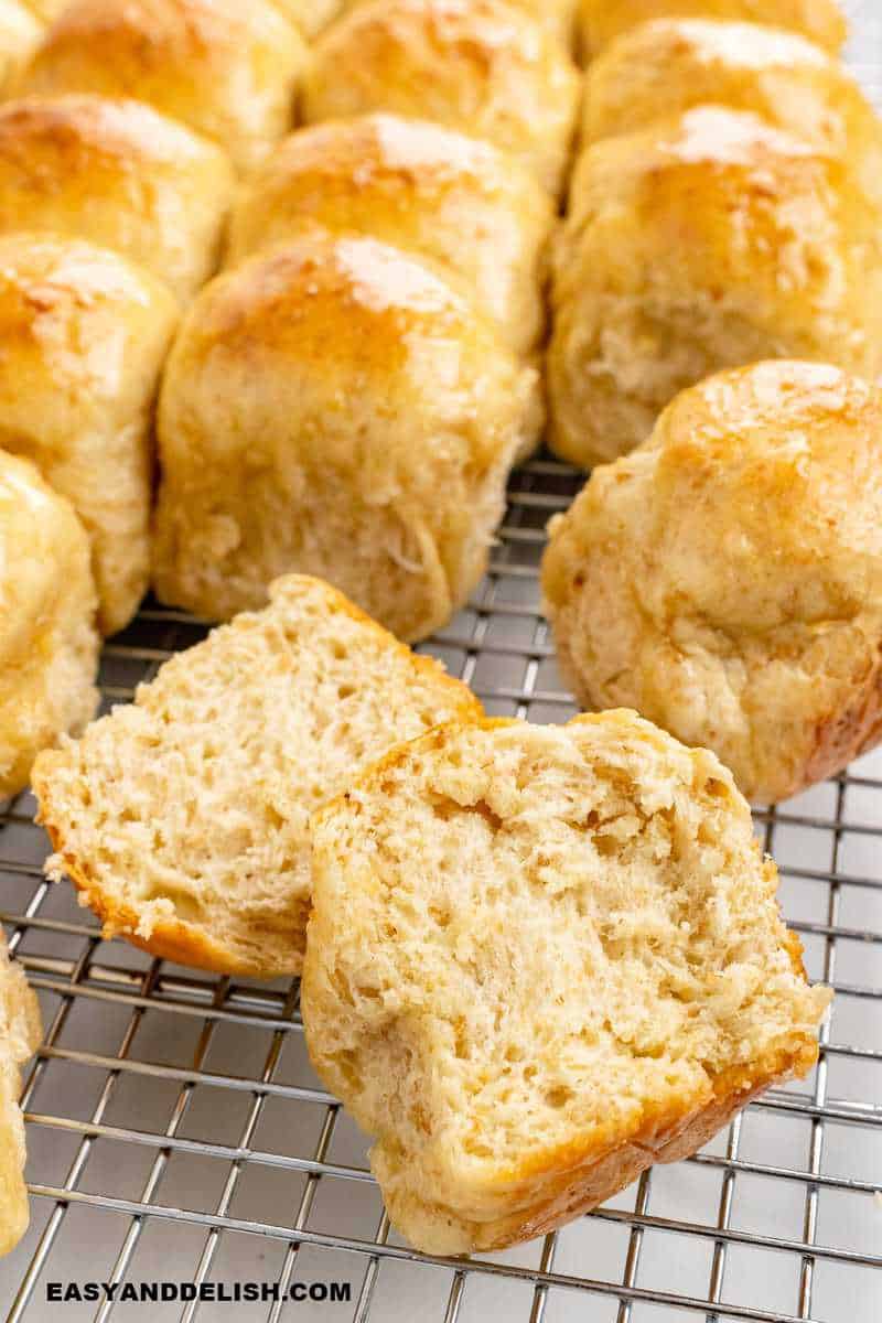 oatmeal rolls on a cooling rack with ine of them sliced in half