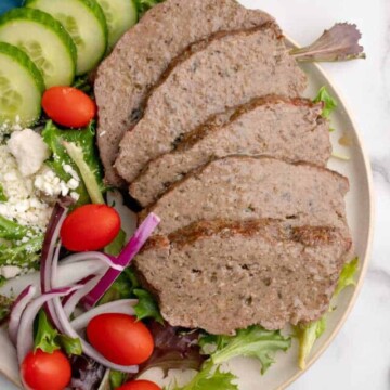 A plate of sliced gyro and veggies