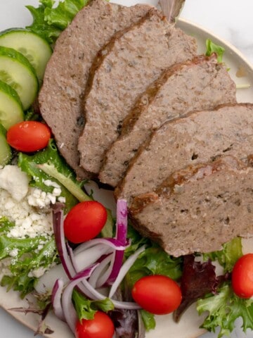 Churrasco grego fatiado servido no prato com uma salada grega