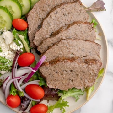 a plate with sliced gyro meat and Greek salad