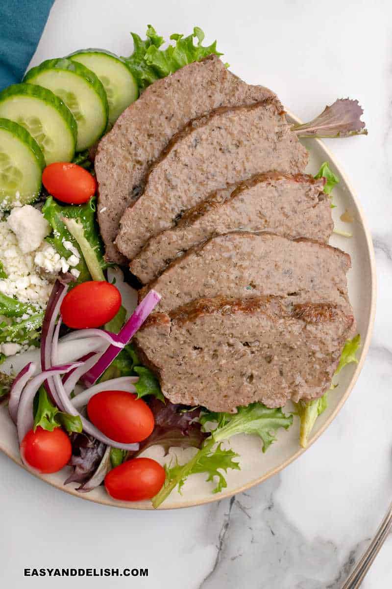 a plate with sliced gyro meat and Greek salad