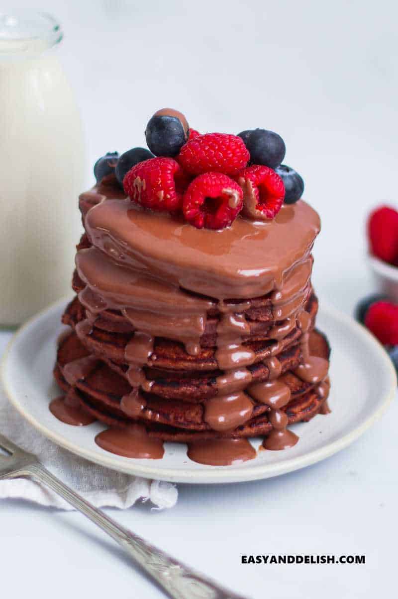 a pile of protein pancakes with melted chocolate and berries