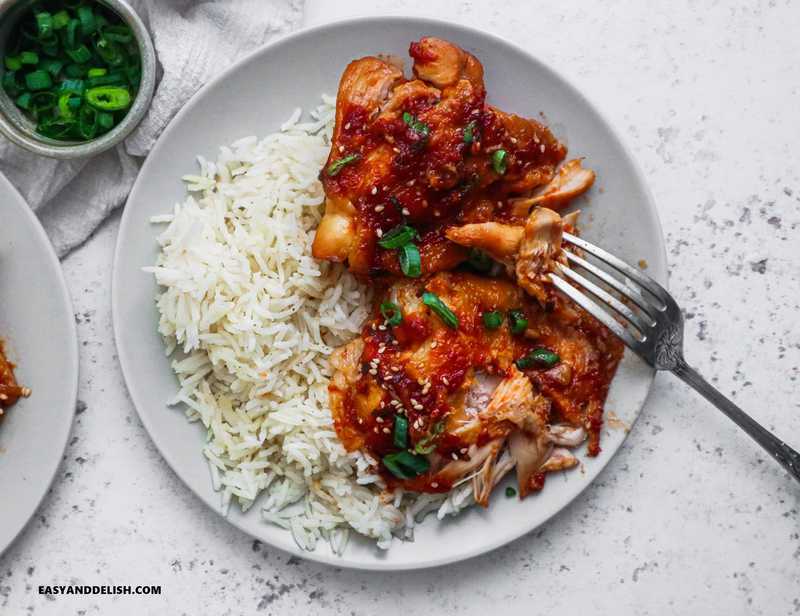 cooked poultry over white rice with garnishes on the side