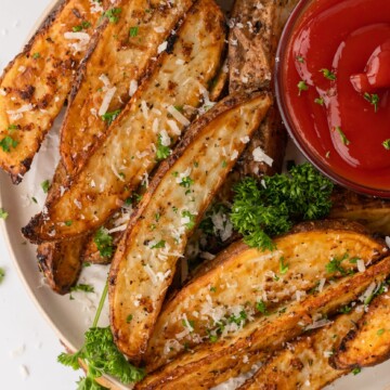 air fryer potato wedges with a side sauce and herbs