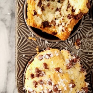 Whole and halved bakery-style chocolate chip muffins in a tin