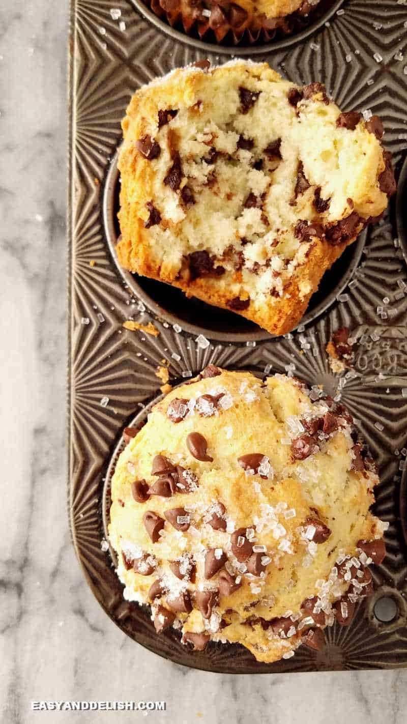 Whole and halved bakery-style chocolate chip muffins in a tin