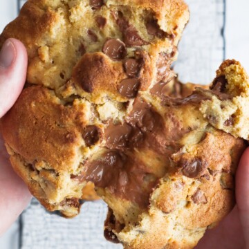 um cookie com gotas de chocolate sendo partido ao meio para mostrar um centro macio