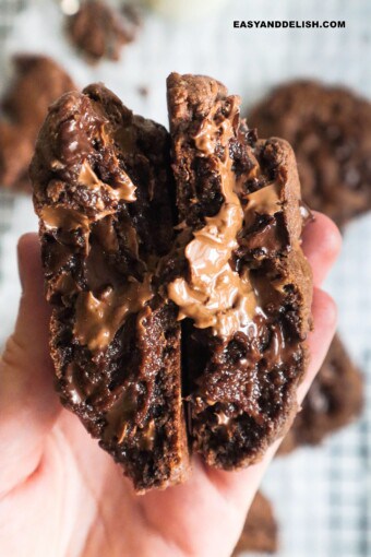 Double chocolate chip cookie cut in half and held to show gooey center