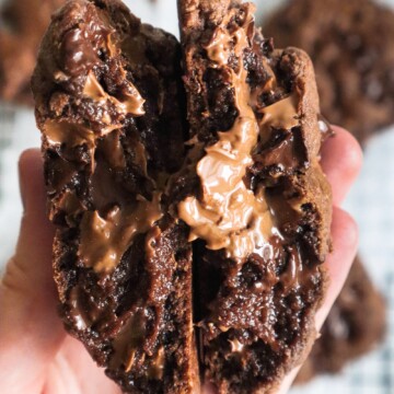 Double chocolate chip cookie cut in half and held to show gooey center