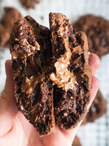 Double chocolate chip cookie cut in half and held to show gooey center