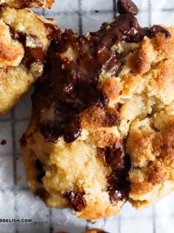 close up of a chocolate chip walnut cookie cut in half and showing puddles of melty chocolate