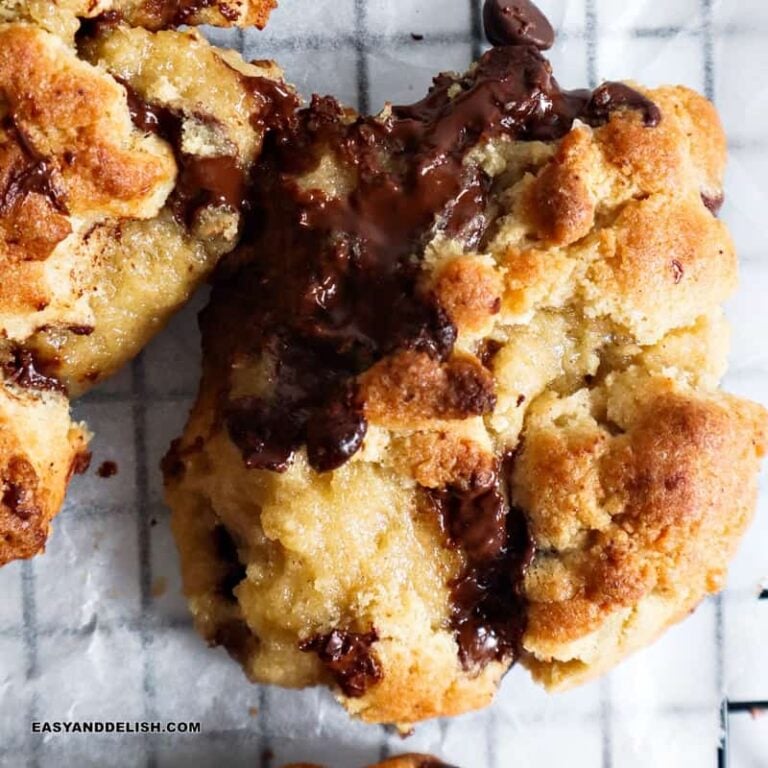 close up of a chocolate chip walnut cookie cut in half and showing puddles of melty chocolate