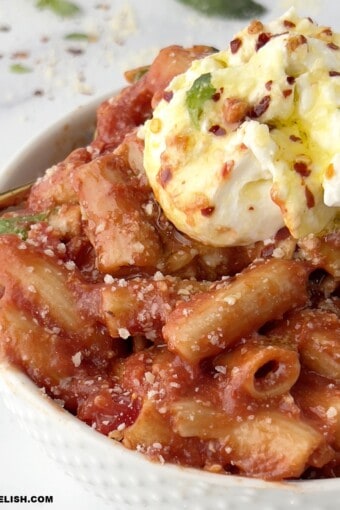 close up of a bowl of penne pomodoro with burrata on top