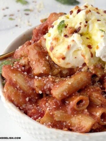 close up of a bowl of penne pomodoro with burrata on top