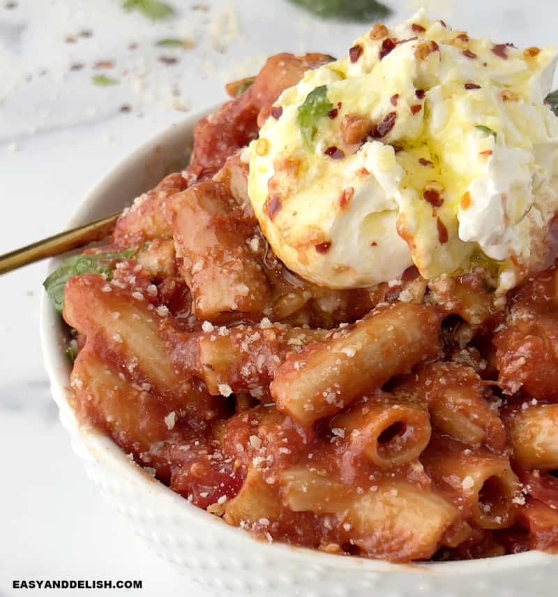 close up of a bowl of penne pomodoro with burrata on top