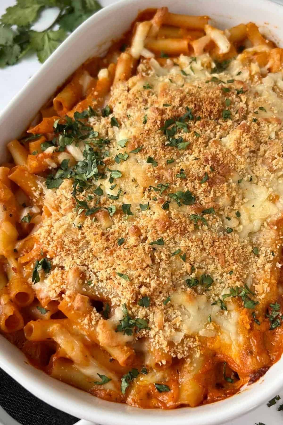 Cheesy baked ziti with tomato sauce, melted cheese, crisp breadcrumbs, and chopped parsley.