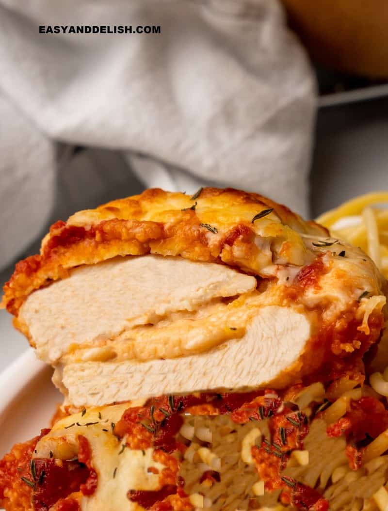 filé de frango a parmegiana recheado com queijo e partido a metade em um prato