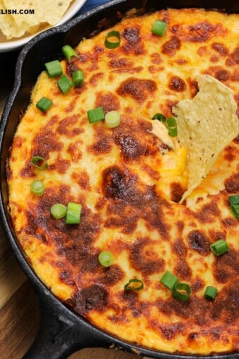 close up of a skillet with keto buffalo chicken dip with a keto tortilla chip on top