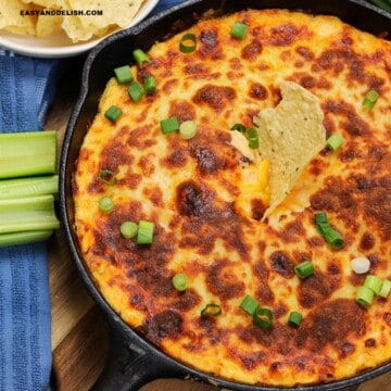 close up of a skillet with keto buffalo chicken dip with a keto tortilla chip on top