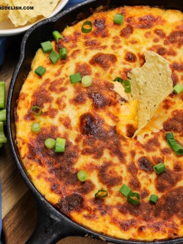 close up of a skillet with keto buffalo chicken dip with a keto tortilla chip on top
