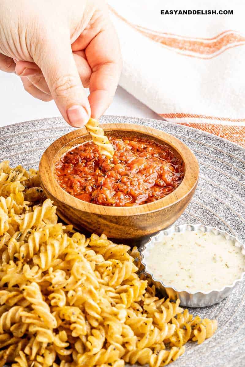 pasta chips dipped in a bowl of spicy marinara sauce