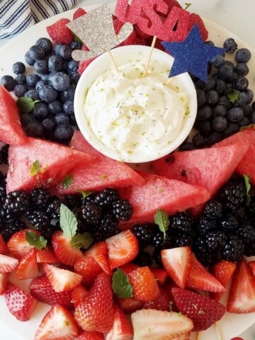 close up of keto cream cheese fruit dip with fruits around decorated for the fourth of july