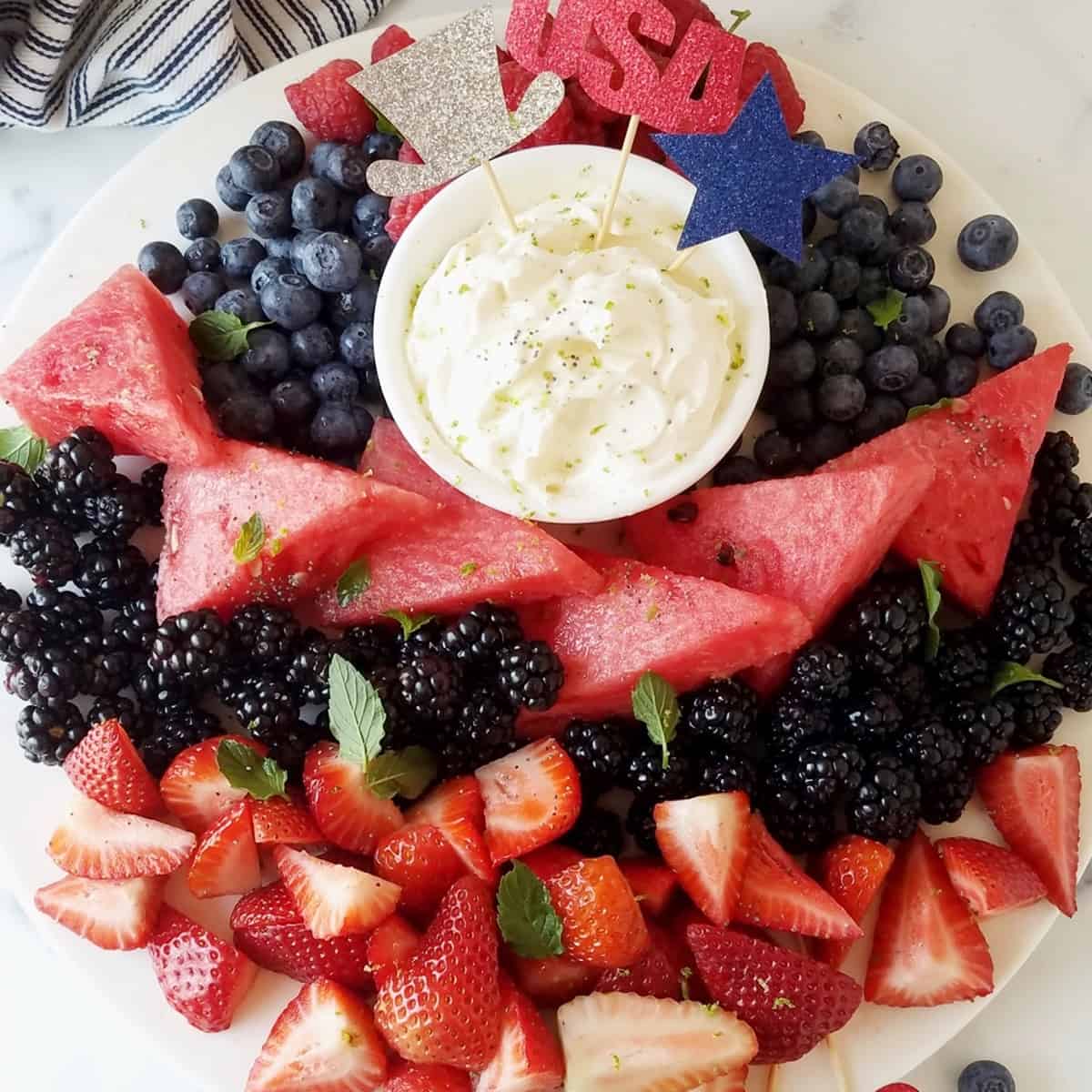 close up of keto cream cheese fruit dip with fruits around decorated for the fourth of july