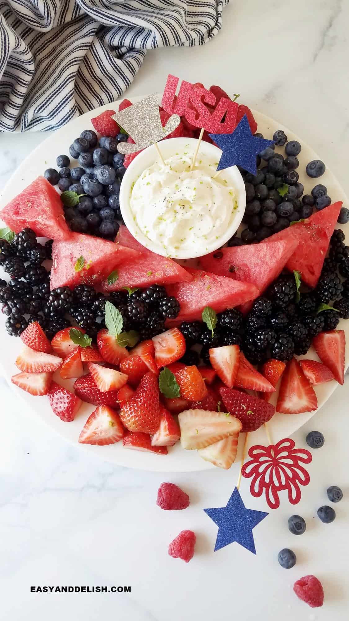 a platter with berries and a bowl of cream cheese fruit dip