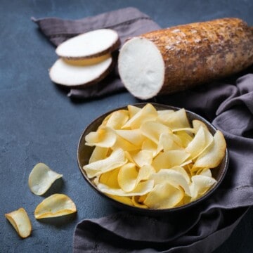 uma tigela com chips de mandioca e uma macaxeira ou aipim fatiado