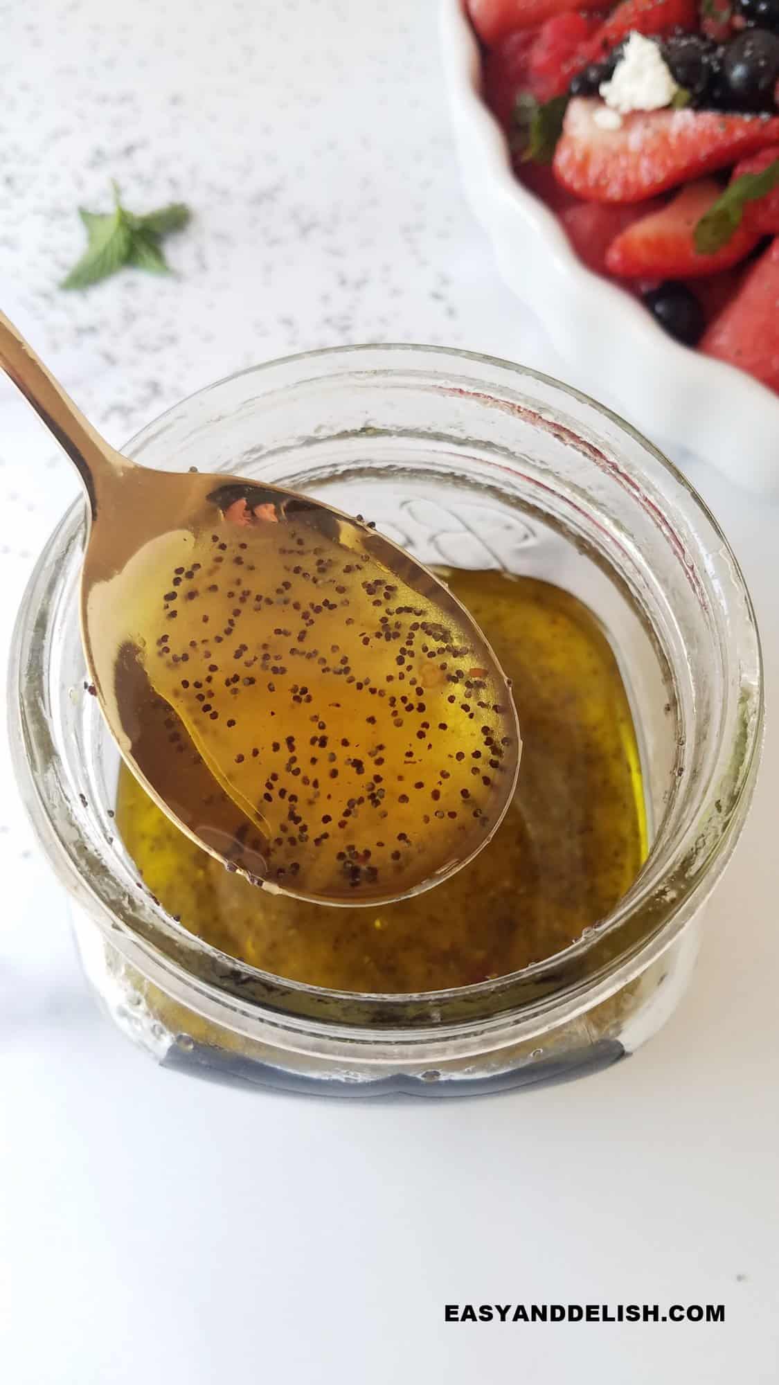 a spoon of poppy seed dressing over a jar