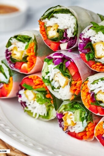 close up of a pile of summer, fresh Vietnamese spring rolls with peanut sauce